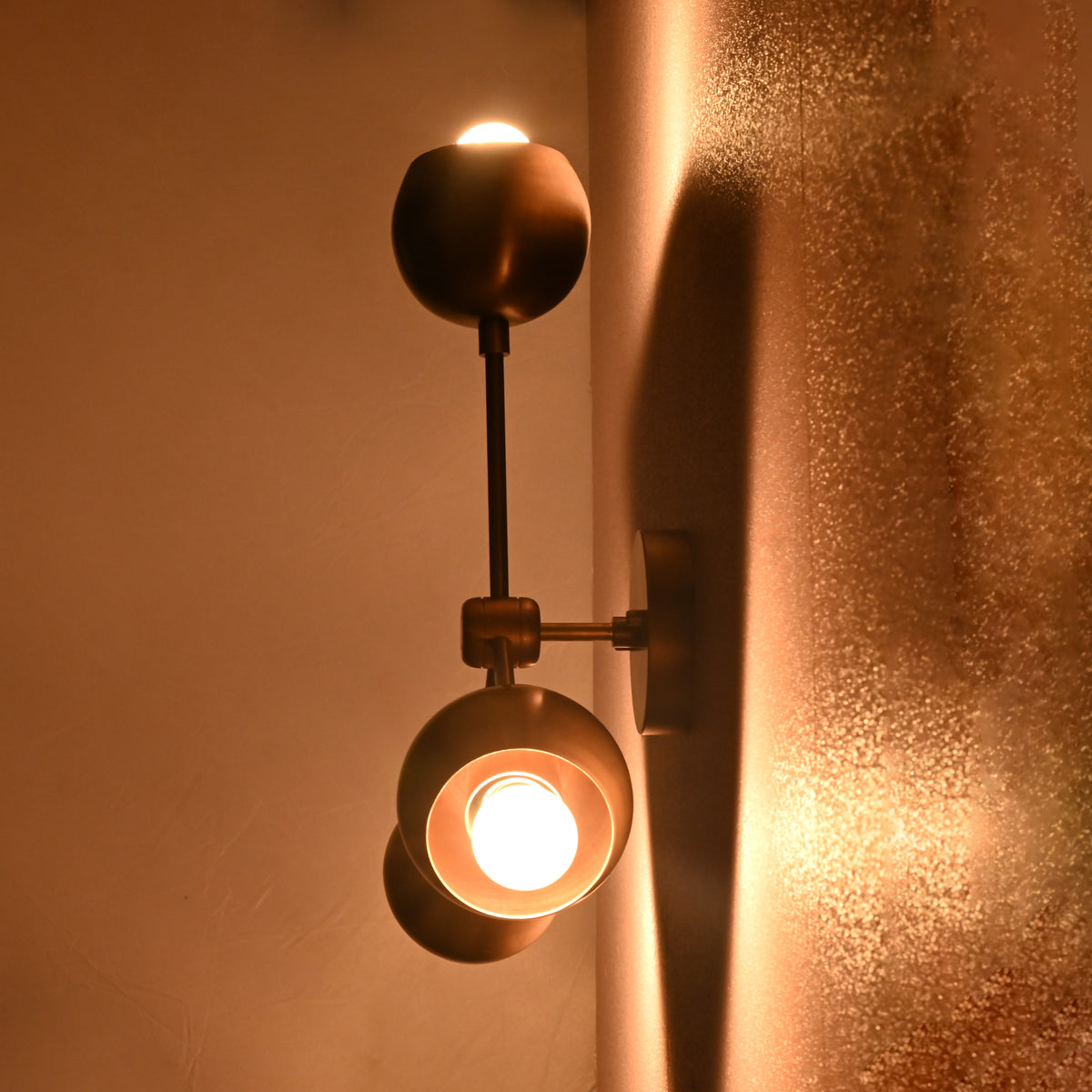 Brass flush mount ceiling light viewed vertically from below, with warm glowing spherical brass shades casting soft light.