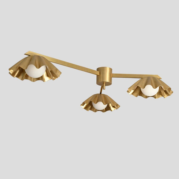 Handmade brass chandelier with three ruffled shades and white globes, viewed from the front, showcasing its elegant modern design.