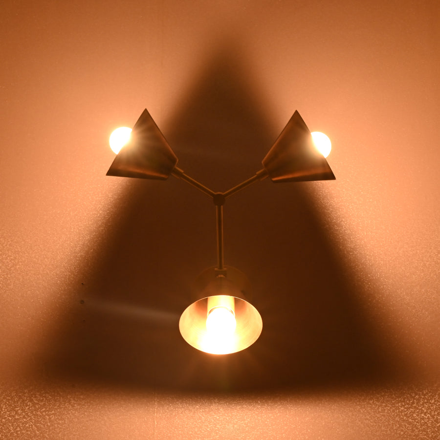 Elegant brass wall sconce with three conical shades arranged in a triangular pattern, designed by Brass Leaf Studio.
