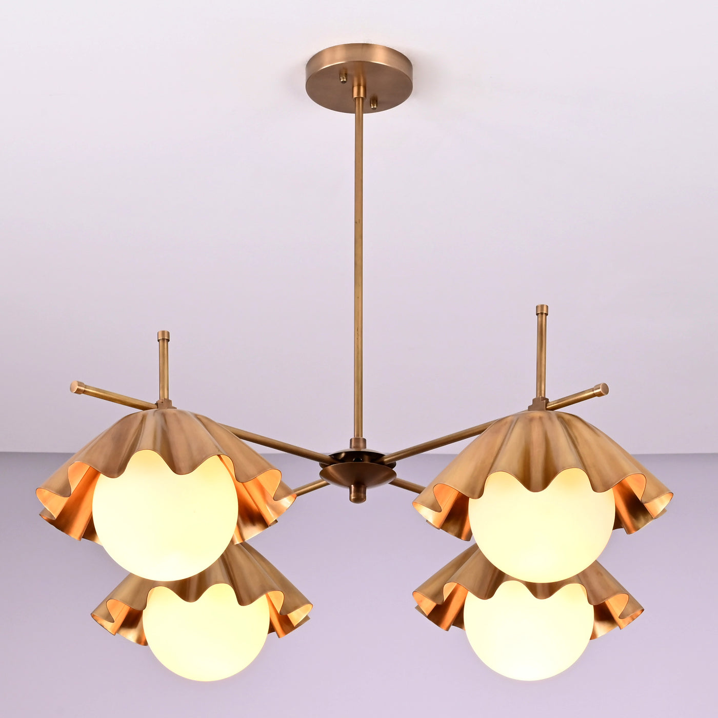 Handmade brass chandelier with four sculpted ruffled shades and frosted globe bulbs, modern ceiling light fixture for living and dining spaces.