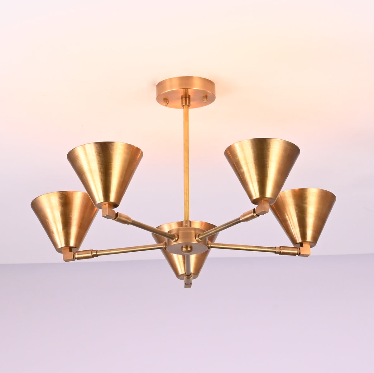 Modern brass chandelier with five upward cone shades in brushed golden finish, mounted on ceiling rod.