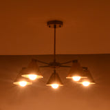 Brass chandelier with five cone shades casting a soft amber glow, ideal for living rooms and bedrooms.