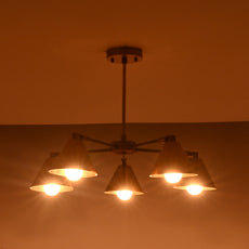 Brass chandelier with five cone shades casting a soft amber glow, ideal for living rooms and bedrooms.