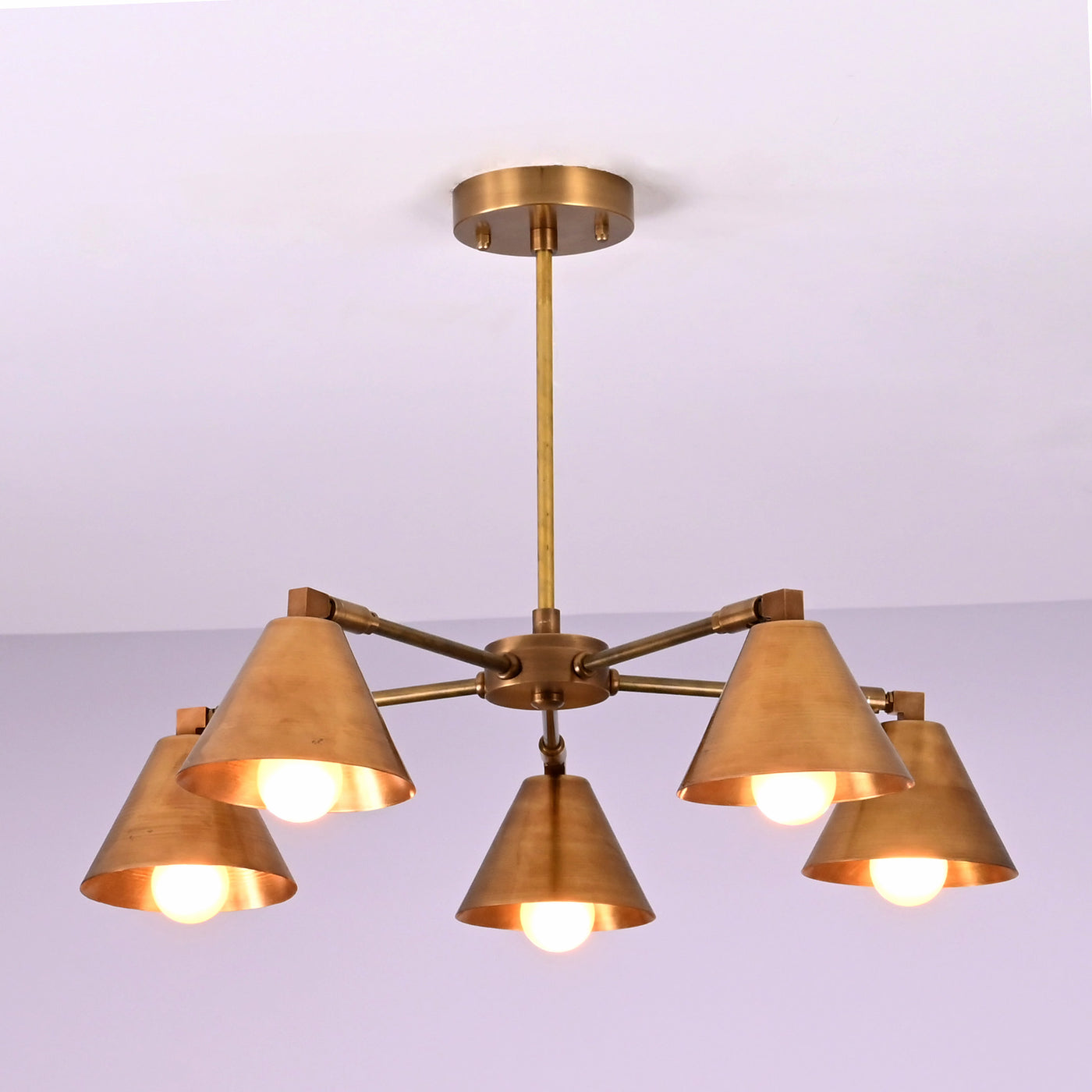 Modern brass chandelier with five cone-shaped shades, minimalist design, and warm golden finish.