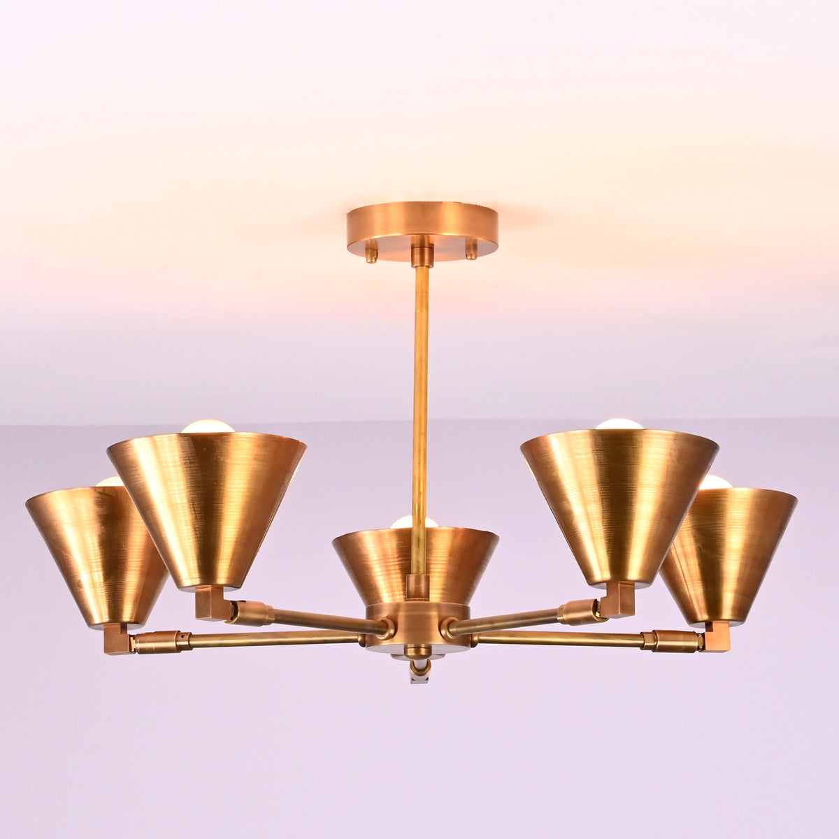 Elegant brass chandelier with five cone-shaped shades in a brushed finish, perfect for modern living rooms, dining areas, and bedrooms.