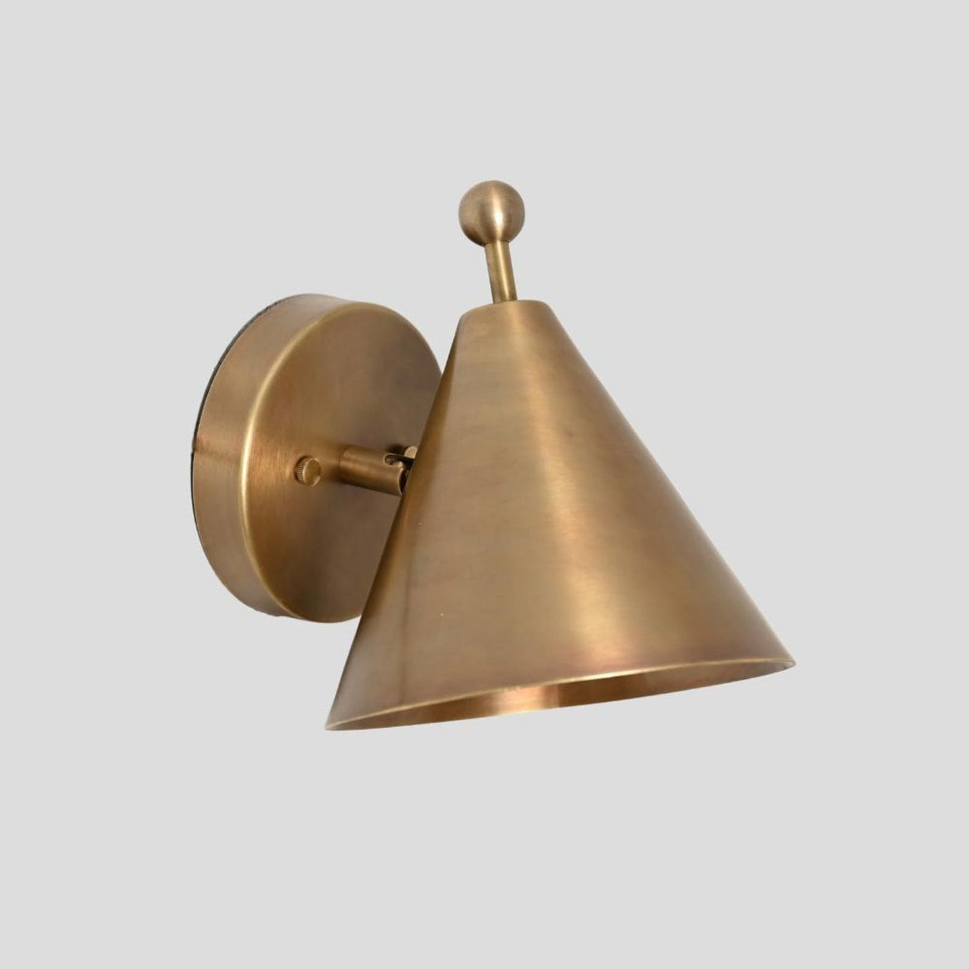 Handcrafted solid brass cone wall sconce with a ball accent on top, mounted on a round brass base, shown at a side angle.