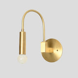 Rear angled view of brass wall sconce with arched arm and exposed bulb, showing circular brass backplate and solid build.
