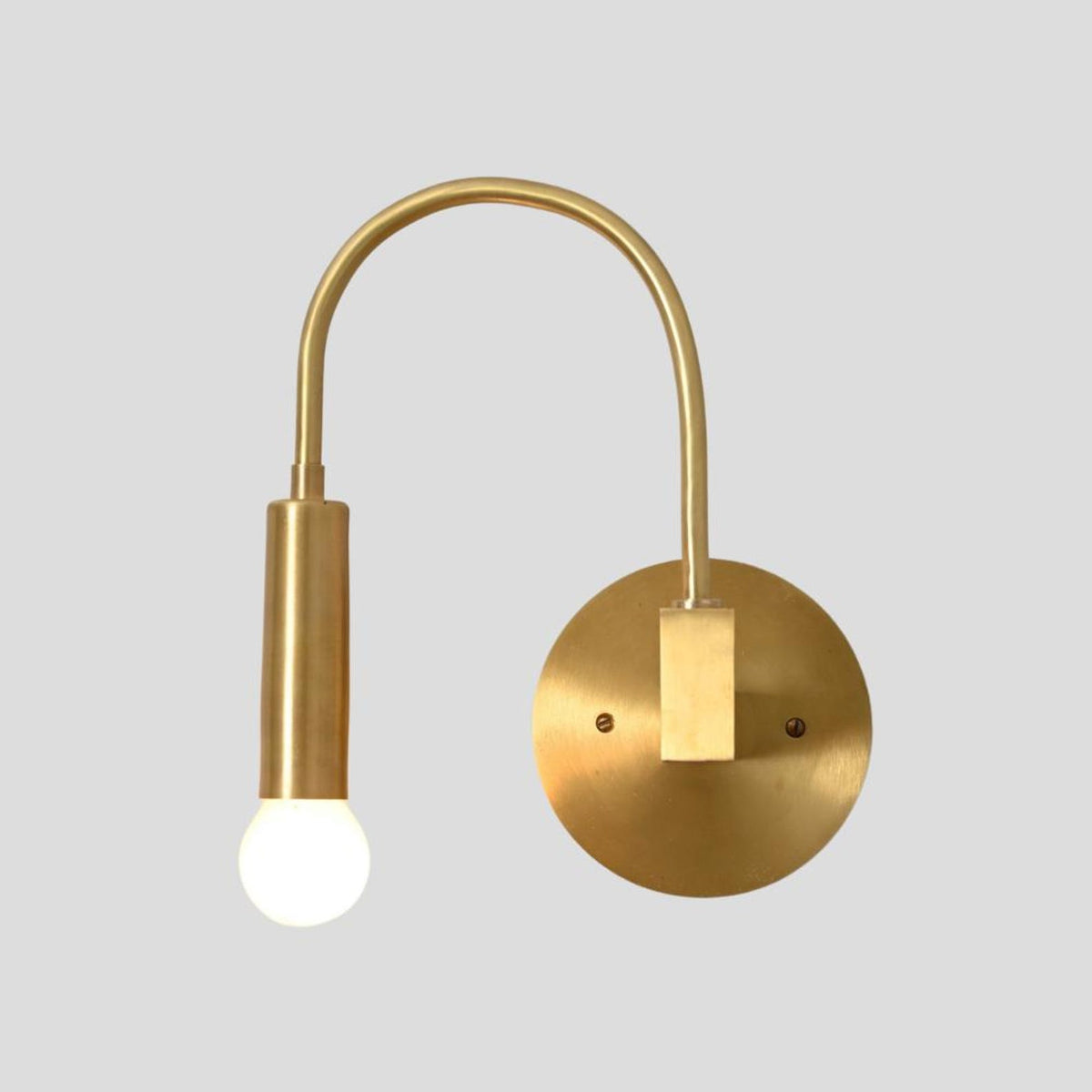 Straight-on view of brass curved arm wall sconce with exposed bulb, modern minimalist lighting design.