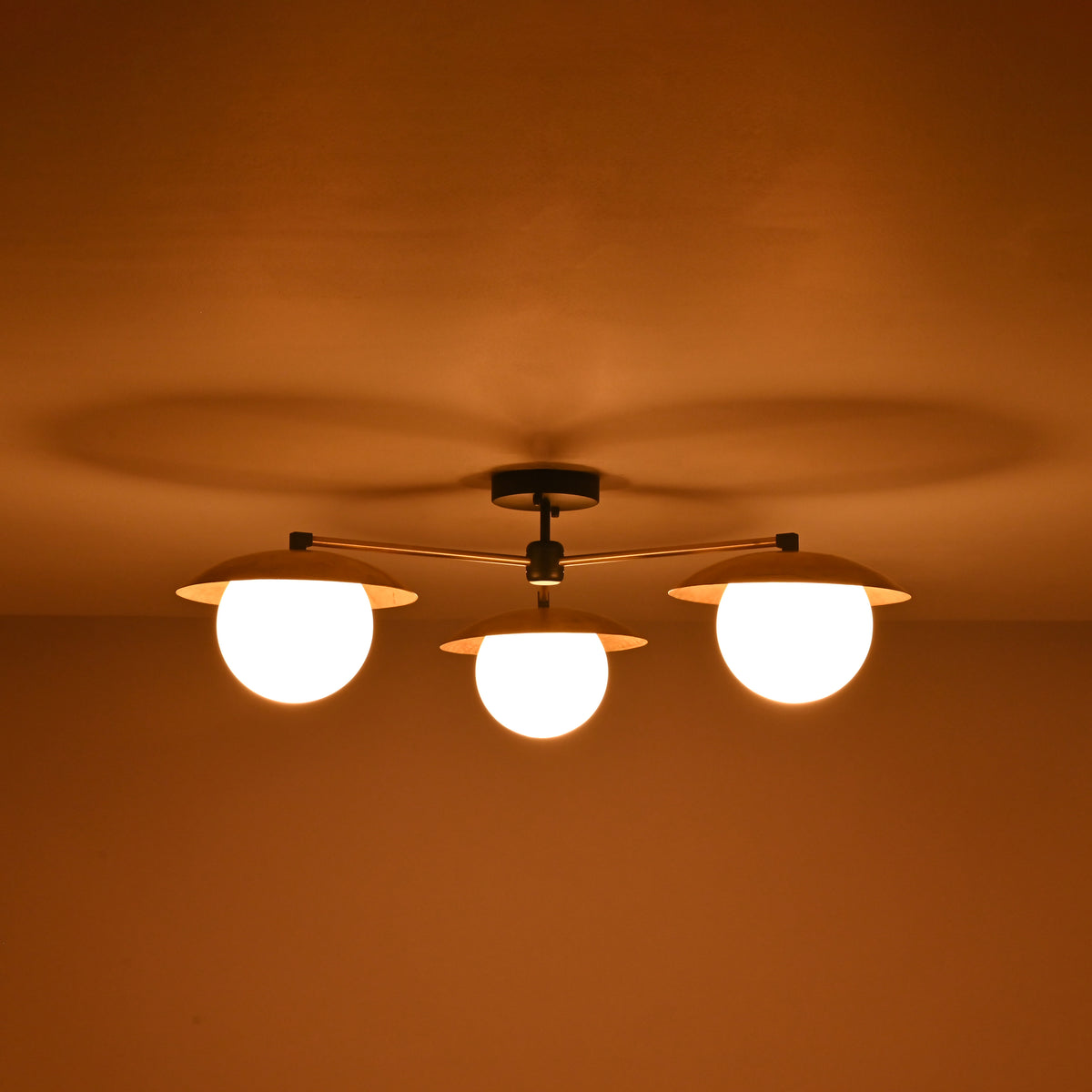 Brass 3-light chandelier with frosted globe bulbs glowing warmly at night, creating soft ambience for modern and classic interiors.