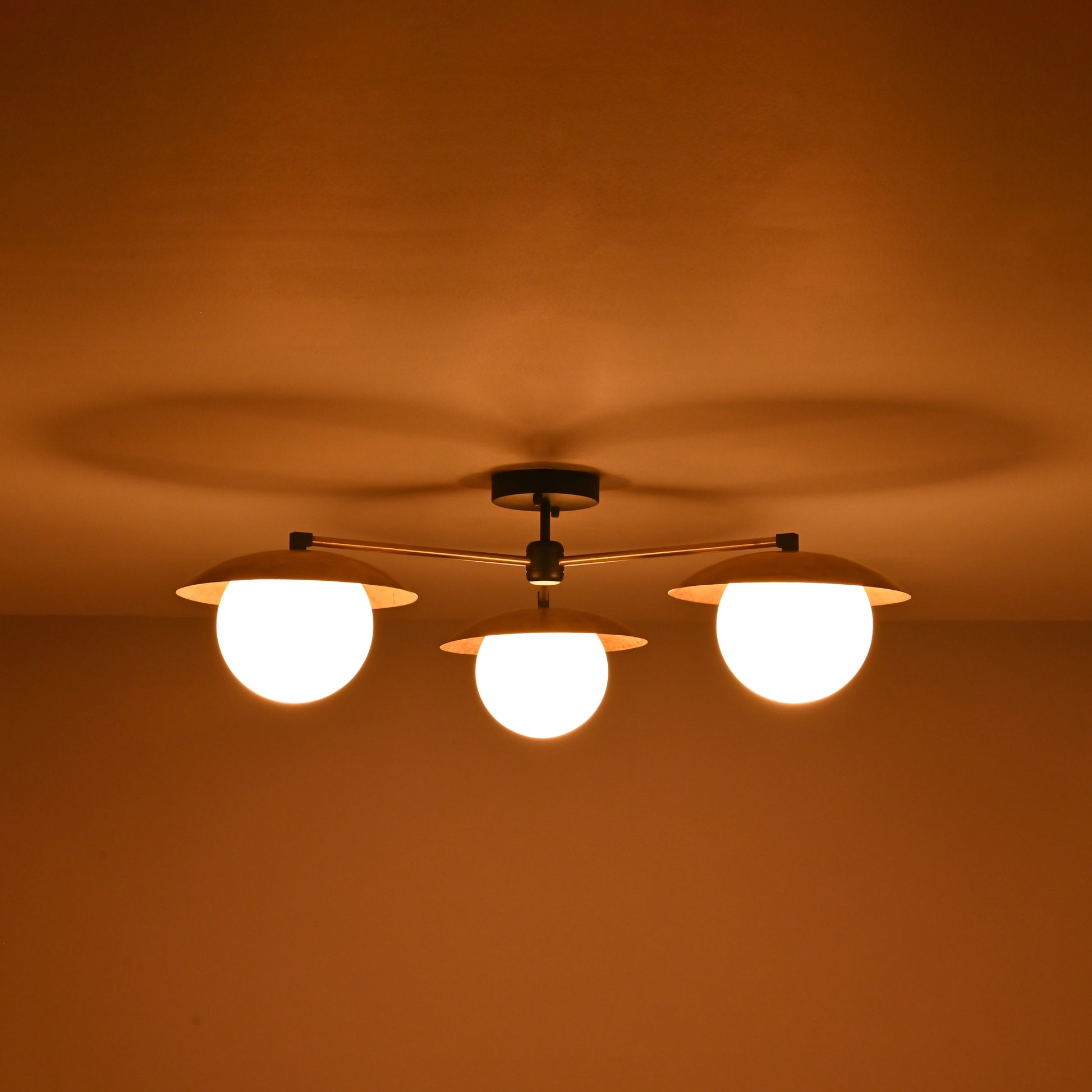 Brass 3-light chandelier with frosted globe bulbs glowing warmly at night, creating soft ambience for modern and classic interiors.