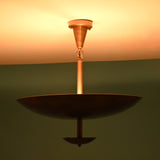 Brass bowl chandelier casting a warm ambient light, viewed from the side against a green background.