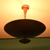 Close-up of a brass bowl chandelier lit warmly, casting an ambient upward glow on the ceiling.