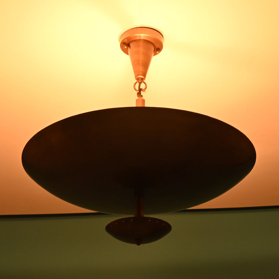 Elegant brass bowl ceiling light in a modern beige-toned living room with warm ambient lighting and contemporary furniture.