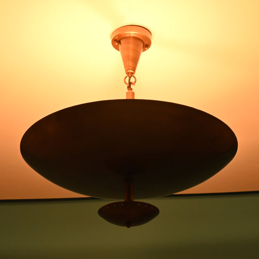 Close-up of a brass bowl chandelier lit warmly, casting an ambient upward glow on the ceiling.