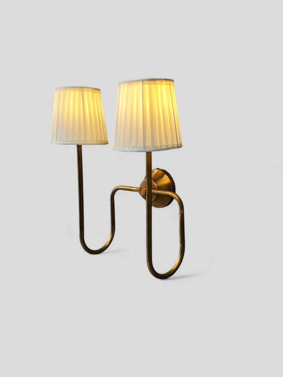Angled side view of brass wall light with pleated shades, handcrafted design blending modern and classic aesthetics.