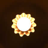 Overhead view of glowing brass flower wall light radiating warm light with wavy petal design.