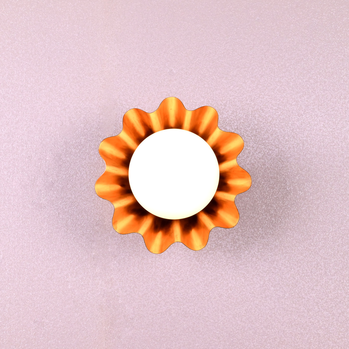 Handmade brass flower-shaped wall light with round bulb, viewed from the front, designed by Brass Leaf Studio.