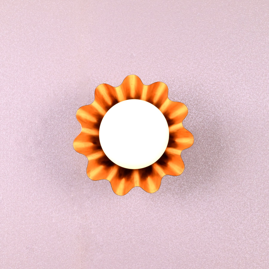 Handmade brass flower-shaped wall light with round bulb, viewed from the front, designed by Brass Leaf Studio.