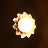 Illuminated brass flower wall sconce creating a warm ambient glow in a dark setting.