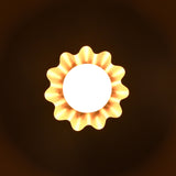 Brass flower-shaped wall light glowing in the dark, casting soft ambient illumination with petal shadow effect.