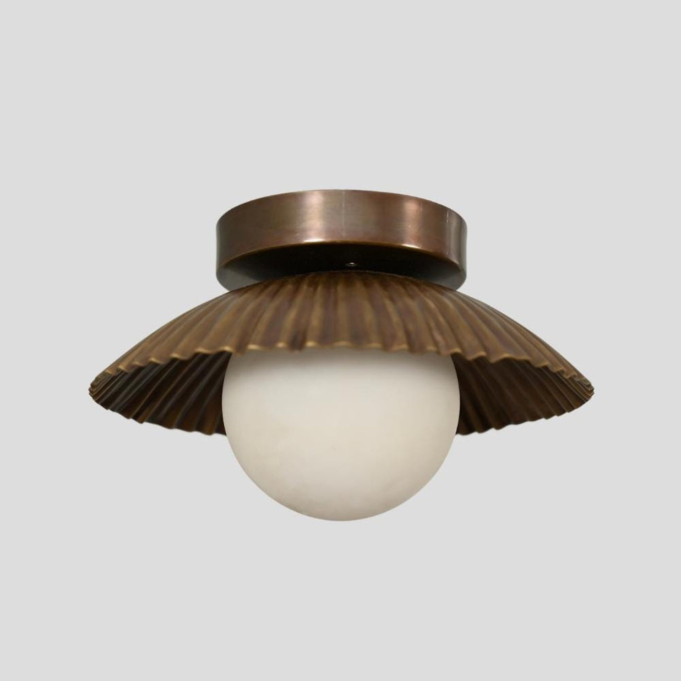 Handmade brass flush mount light with a scalloped shade design, featuring a round white bulb and antique finish, ideal for living rooms and entryways.