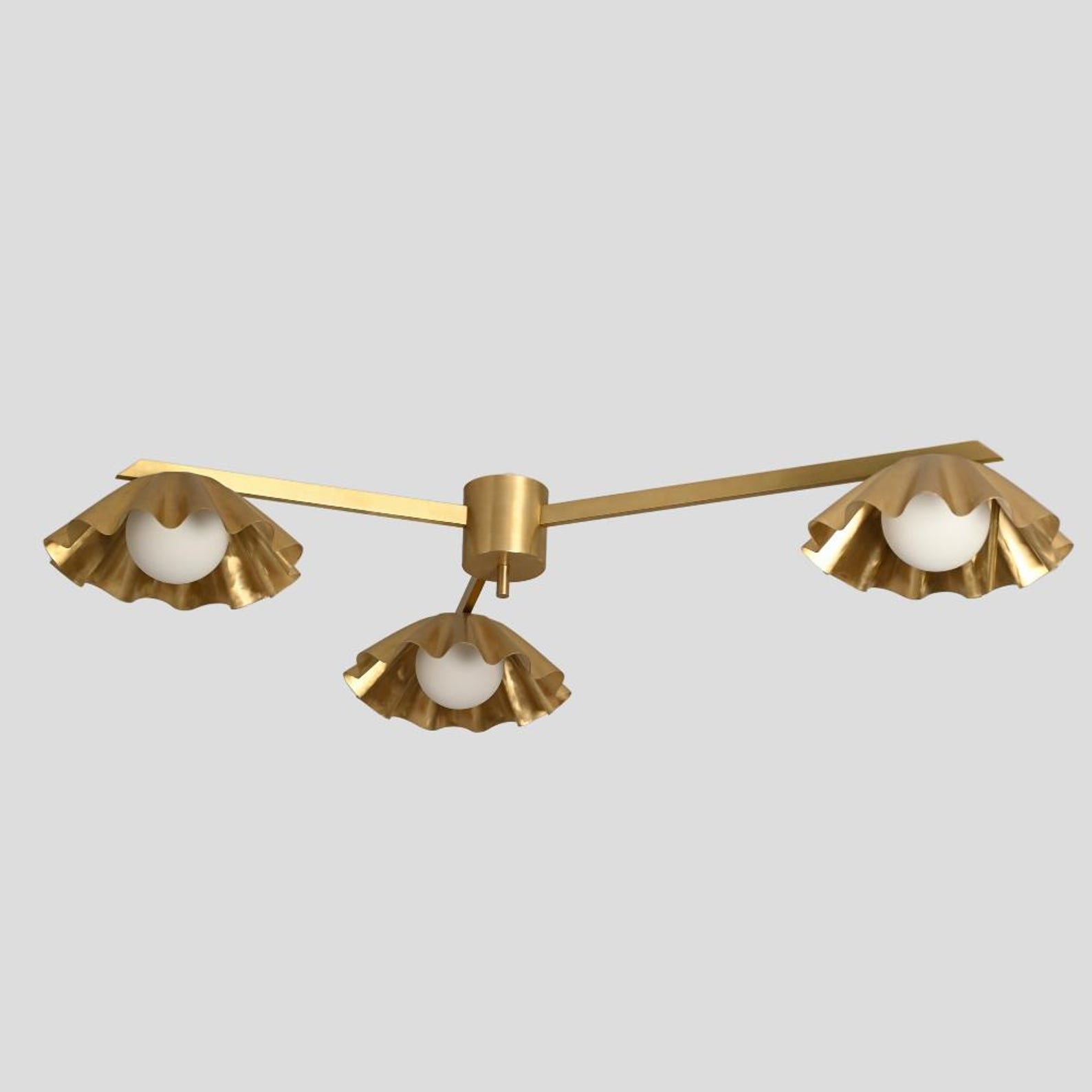 Side profile of a brass chandelier featuring three flowing ruffled shades with soft white globe bulbs.