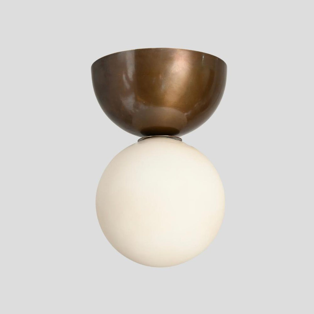 Front-facing view of handcrafted brass flushmount ceiling light featuring frosted globe shade and lacquer-coated brass base.