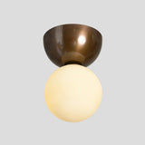 Modern brass flushmount ceiling light with frosted globe shade illuminated, highlighting warm ambient glow and satin brass bowl mount.