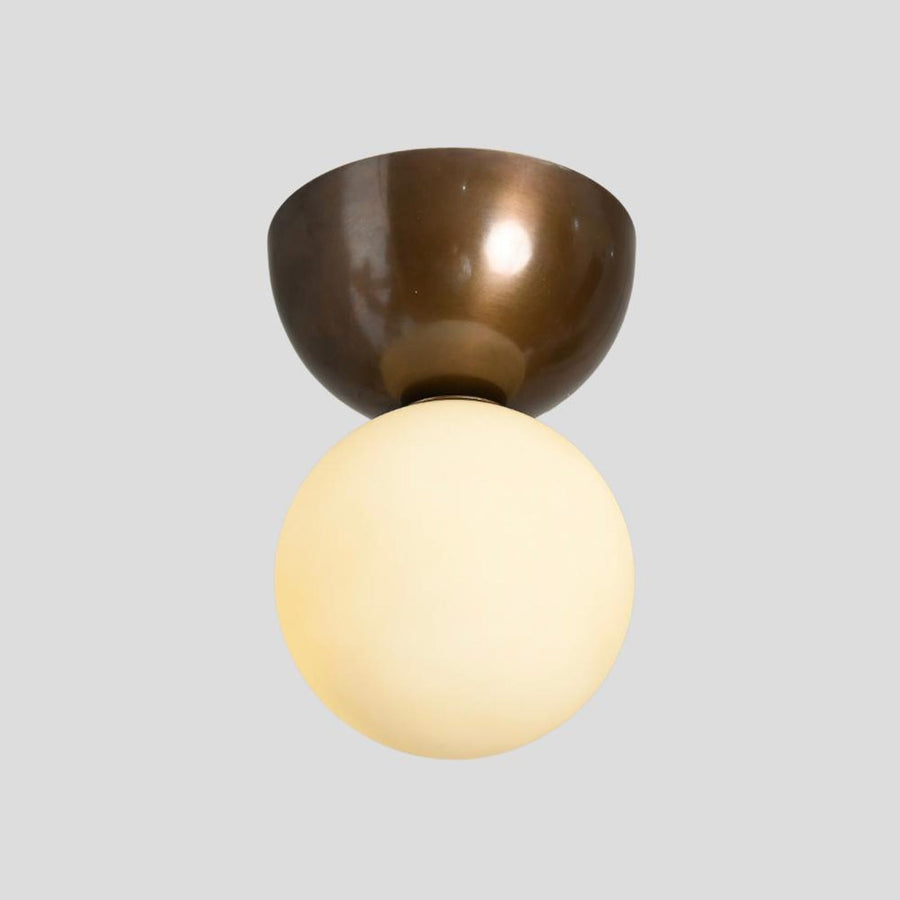 Handmade brass flushmount ceiling light with frosted glass globe, unlit view showing brushed brass bowl base and minimalist design.