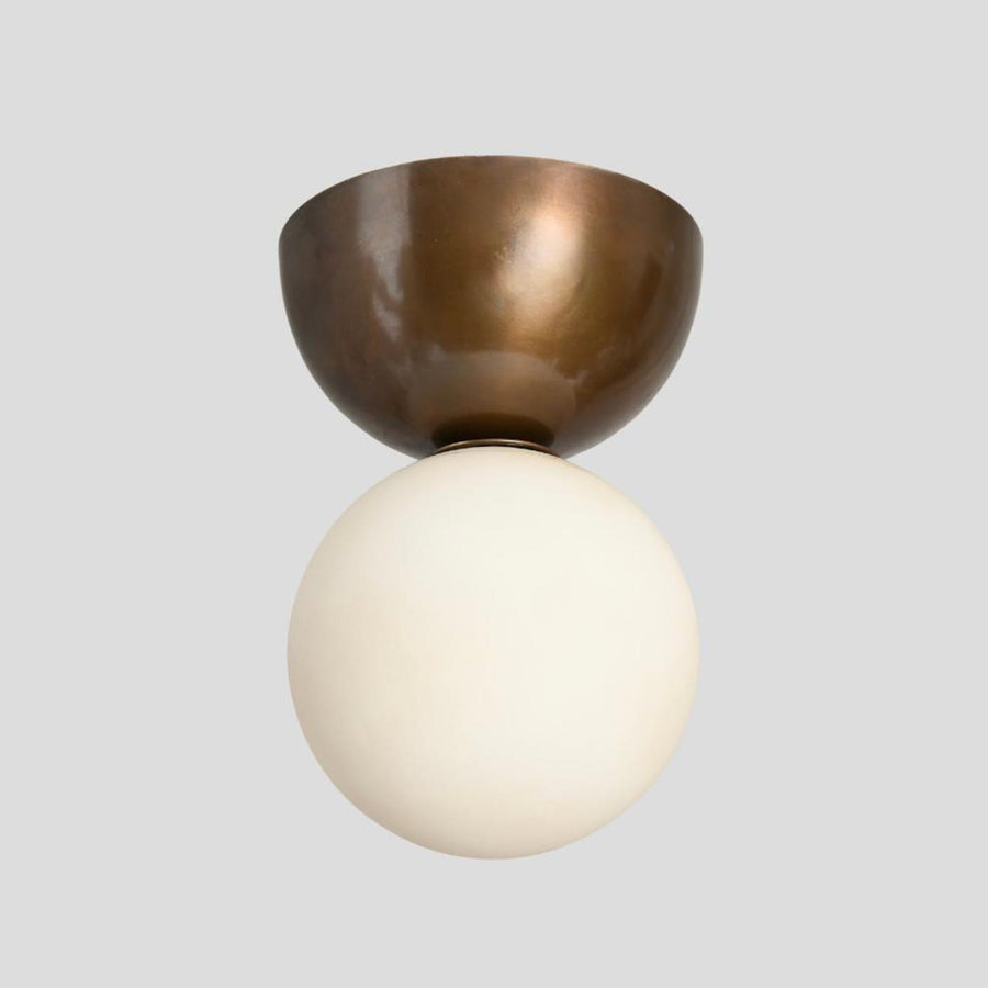Handmade brass flushmount ceiling light with frosted glass globe, unlit view showing brushed brass bowl base and minimalist design.