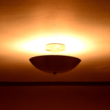 Elegant brushed brass ceiling light glowing warmly in softly lit interior setting