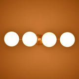 Overhead view of brass chandelier with four glowing frosted globes, radiating soft golden light in a sleek linear design.