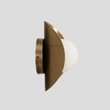 Slim side view of handcrafted brass wall sconce with frosted glass globe shade and brushed brass base.