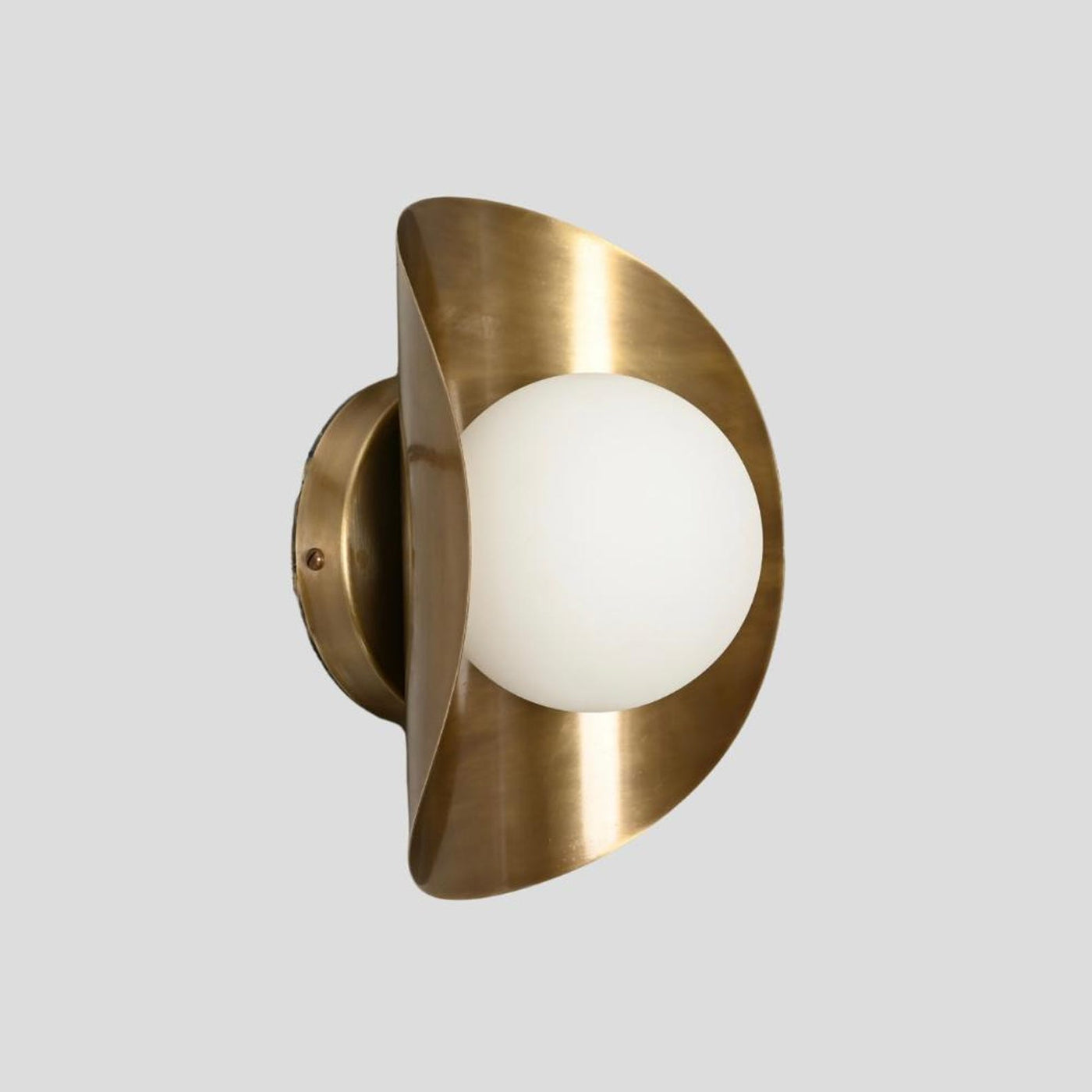 Handmade brass wall sconce with frosted glass globe shade, side profile view showcasing curved brass design.