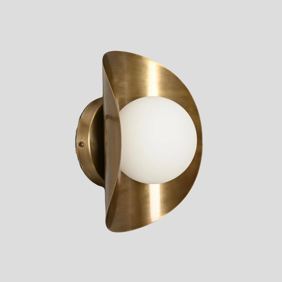 Handmade brass wall sconce with frosted glass globe shade, side profile view showcasing curved brass design.