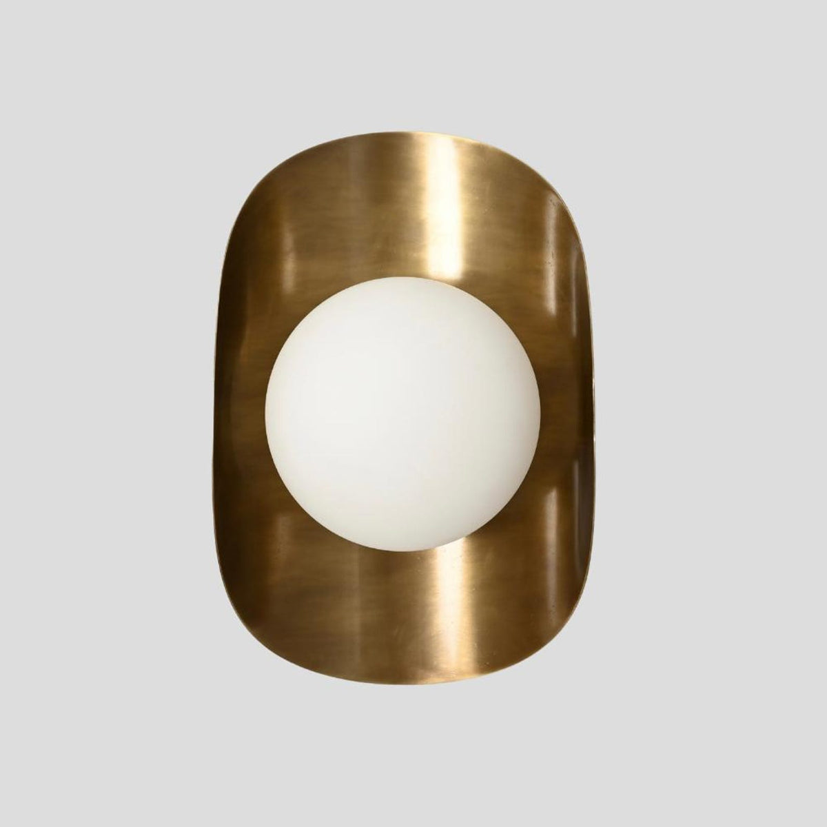 Vertical front view of handmade brass wall sconce with frosted glass globe shade set in brushed brass frame.