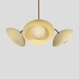 Unique view of a modern brass chandelier with cream dome shades and spherical glass light bulbs.