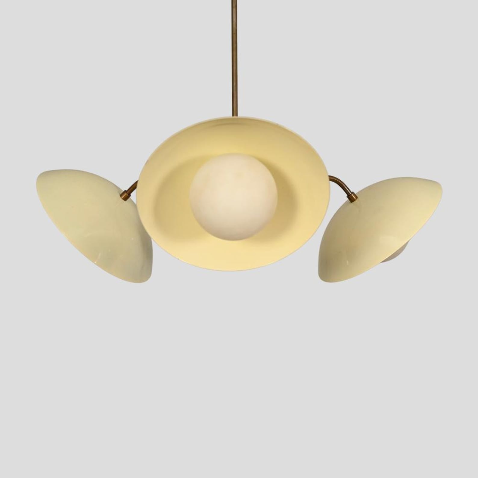 Unique view of a modern brass chandelier with cream dome shades and spherical glass light bulbs.
