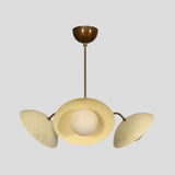 Artistic underside view of a 3-light brass chandelier featuring cream bowl shades and central brass sphere body.