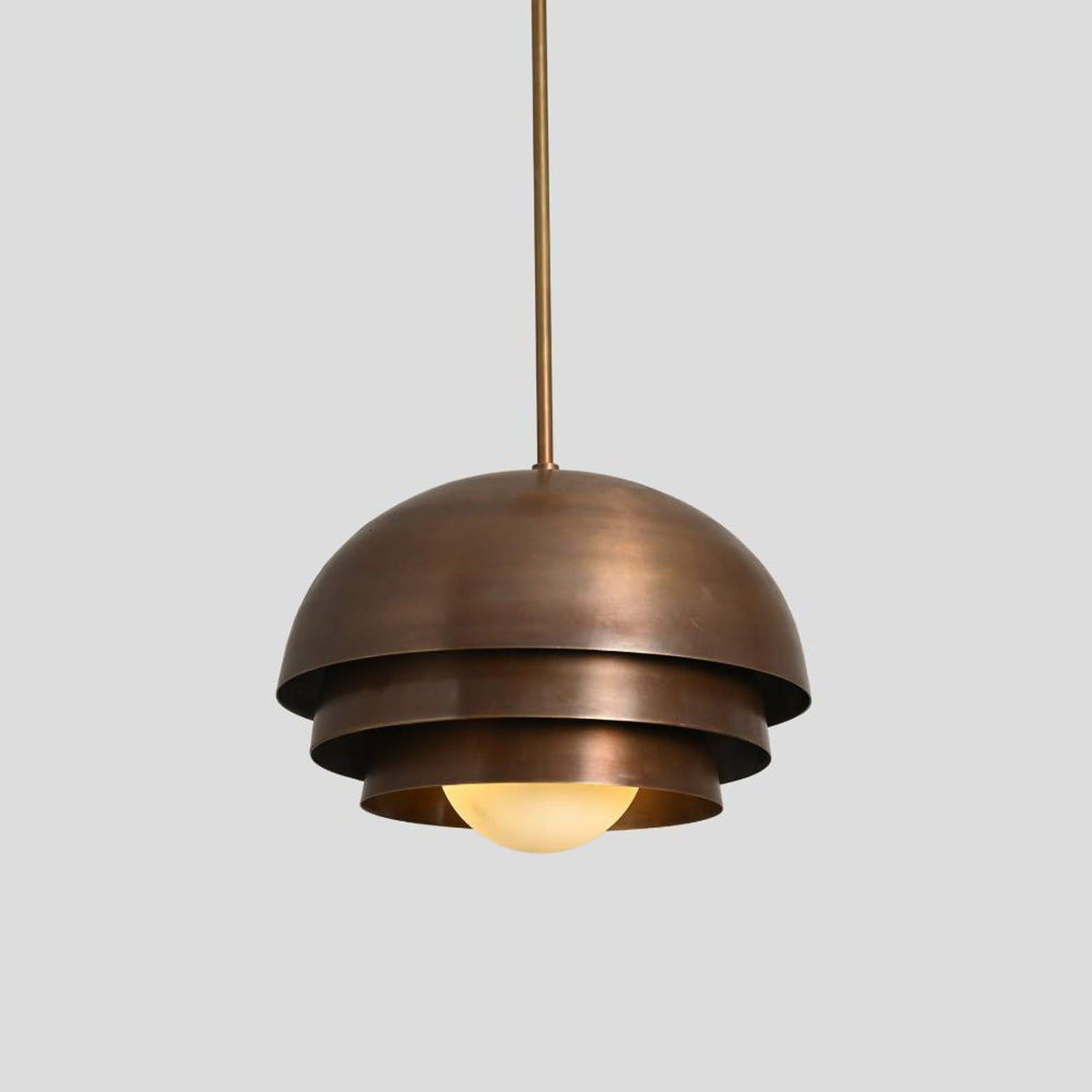 Modern brass dome hanging lamp with tiered layers and warm light glow, handmade by Brass Leaf Studio.