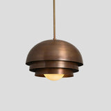 Vintage dome pendant light in layered brass design with warm glowing bulb by Brass Leaf Studio.