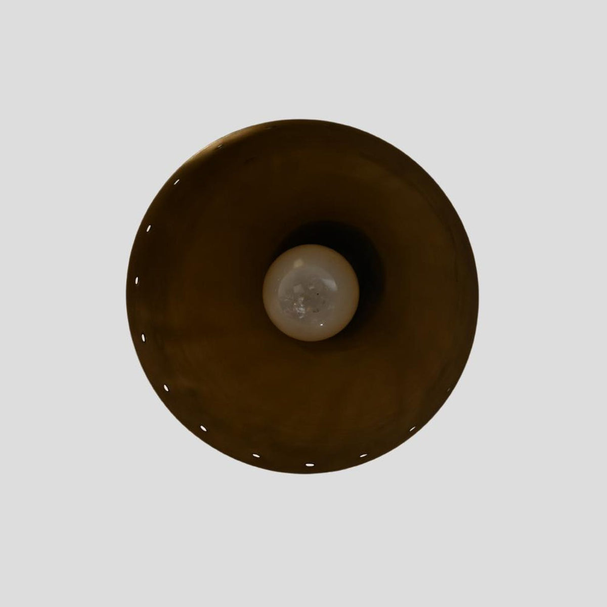 Underside view of brass perforated ceiling light showcasing inner bulb placement and handcrafted brass detailing.