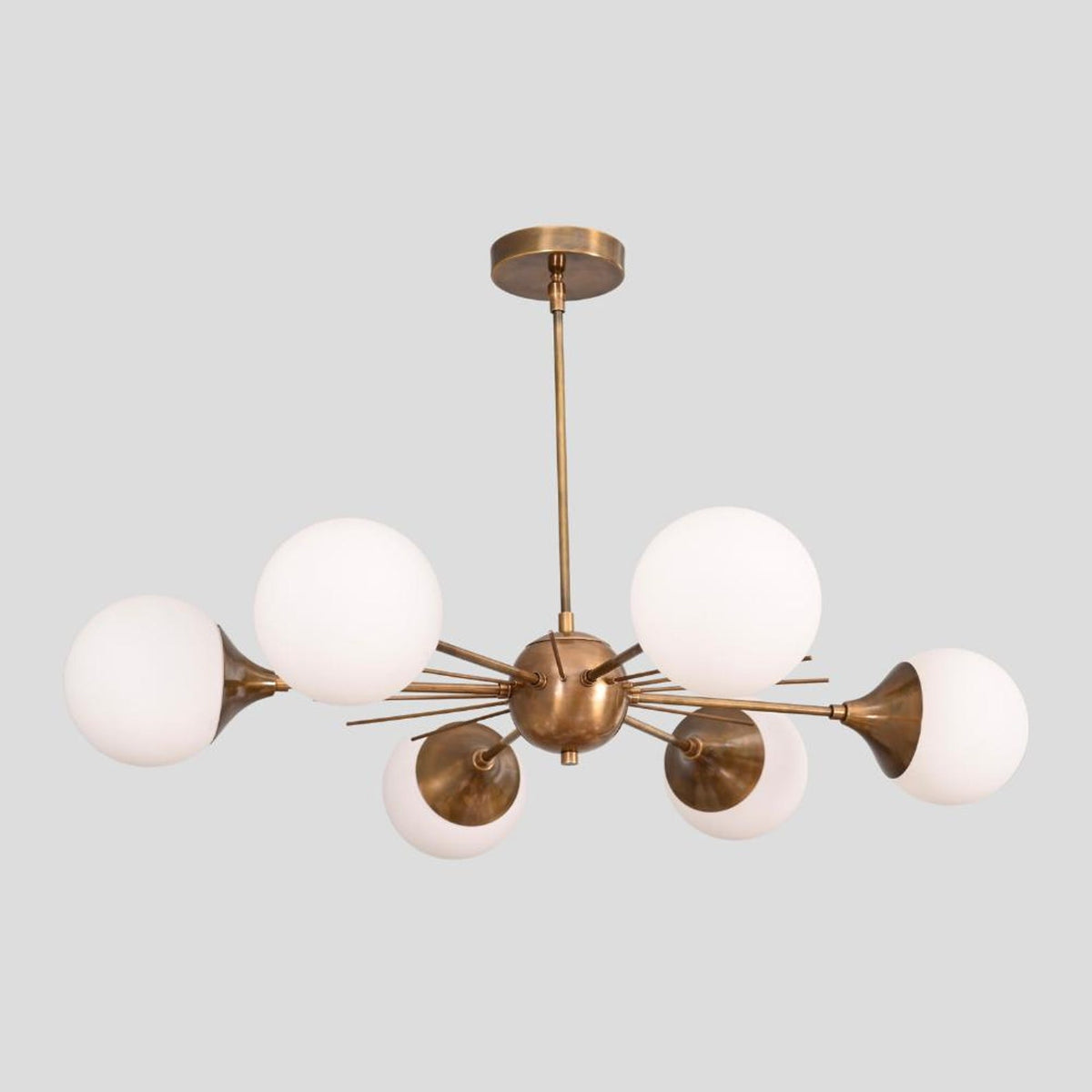 Brass Sputnik chandelier featuring six white glass globes and a central brass sphere with extended arms, blending mid-century modern and industrial design.