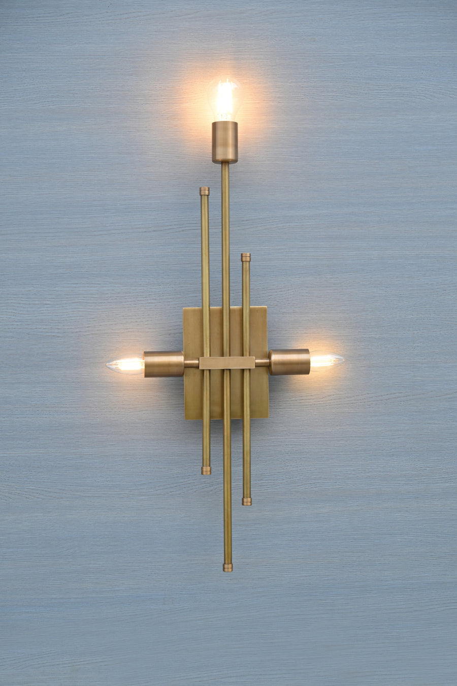 Handmade brass wall sconce featuring a vertical rod design with three light holders, modern industrial style by Brass Leaf Studio.