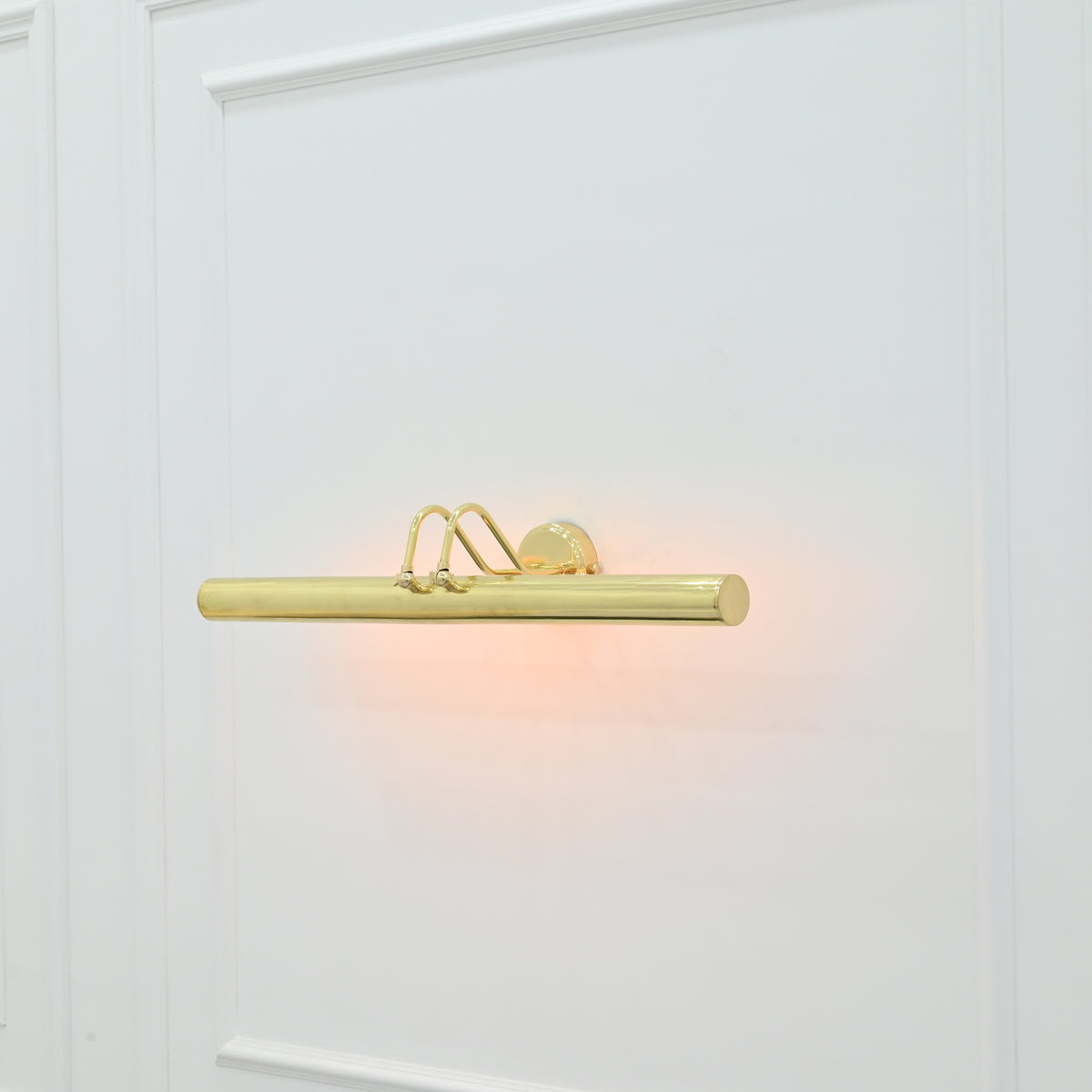 Angled front view of Brisbane brass picture light featuring a cylindrical light bar, curved support arms, and round wall mount.
