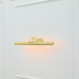 Angled front view of Brisbane brass picture light featuring a cylindrical light bar, curved support arms, and round wall mount.