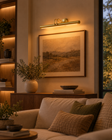 Brisbane 30 inch brass linear picture light mounted above framed landscape artwork in a cozy modern living room with warm ambient lighting.