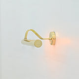 Side profile of Brisbane 4 light polished brass wall-mounted picture light showing decorative curved arms and cylindrical metal shade.