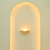Brooklyn polished brass ruffled wall sconce installed inside a tall arched wall niche, creating elegant warm ambient lighting.