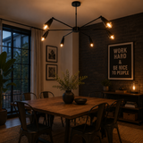 Bruges 6 light matte black multi-arm chandelier illuminated above a dining table in a modern industrial dining room.